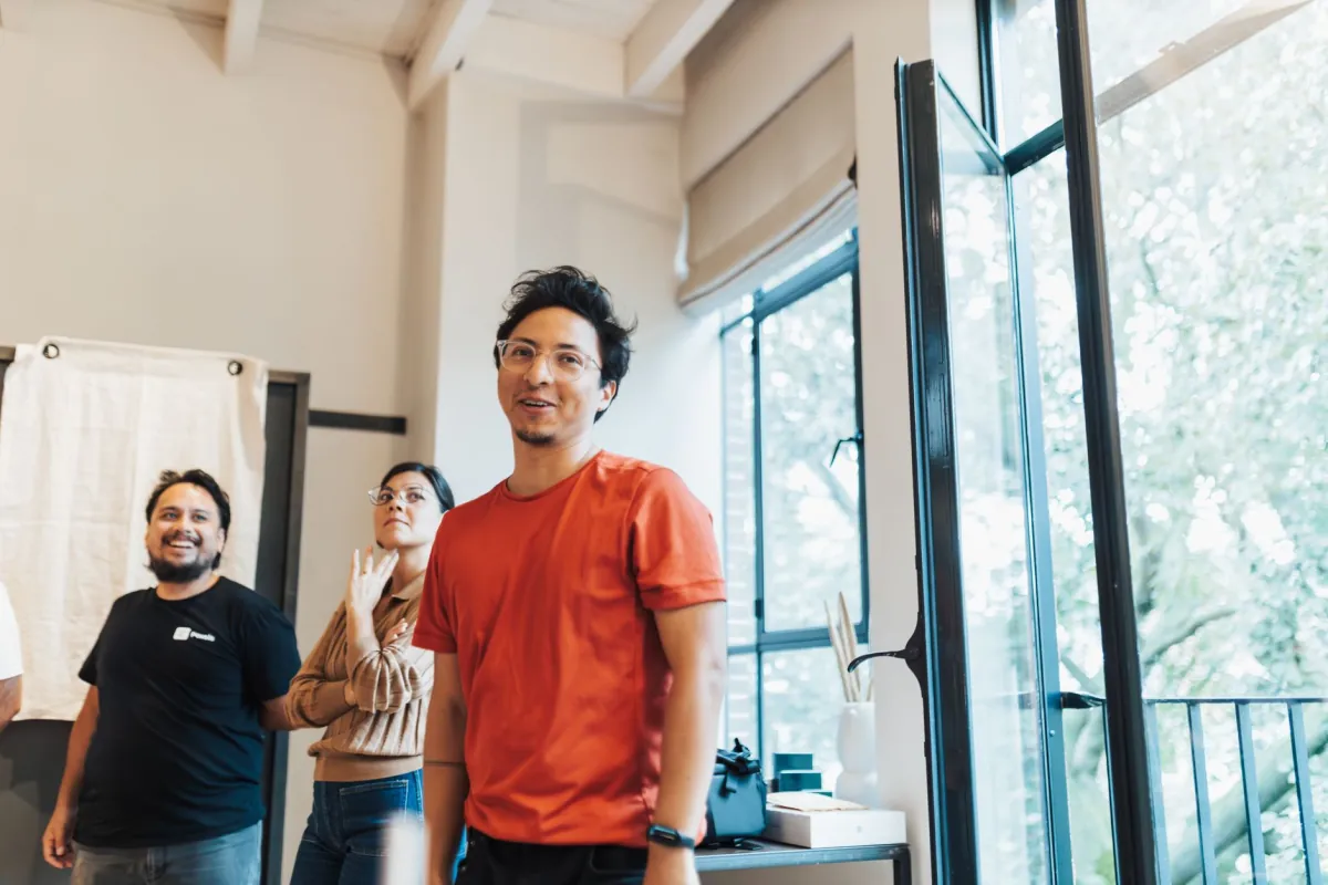Casual group meeting in a bright office with three adults interacting.