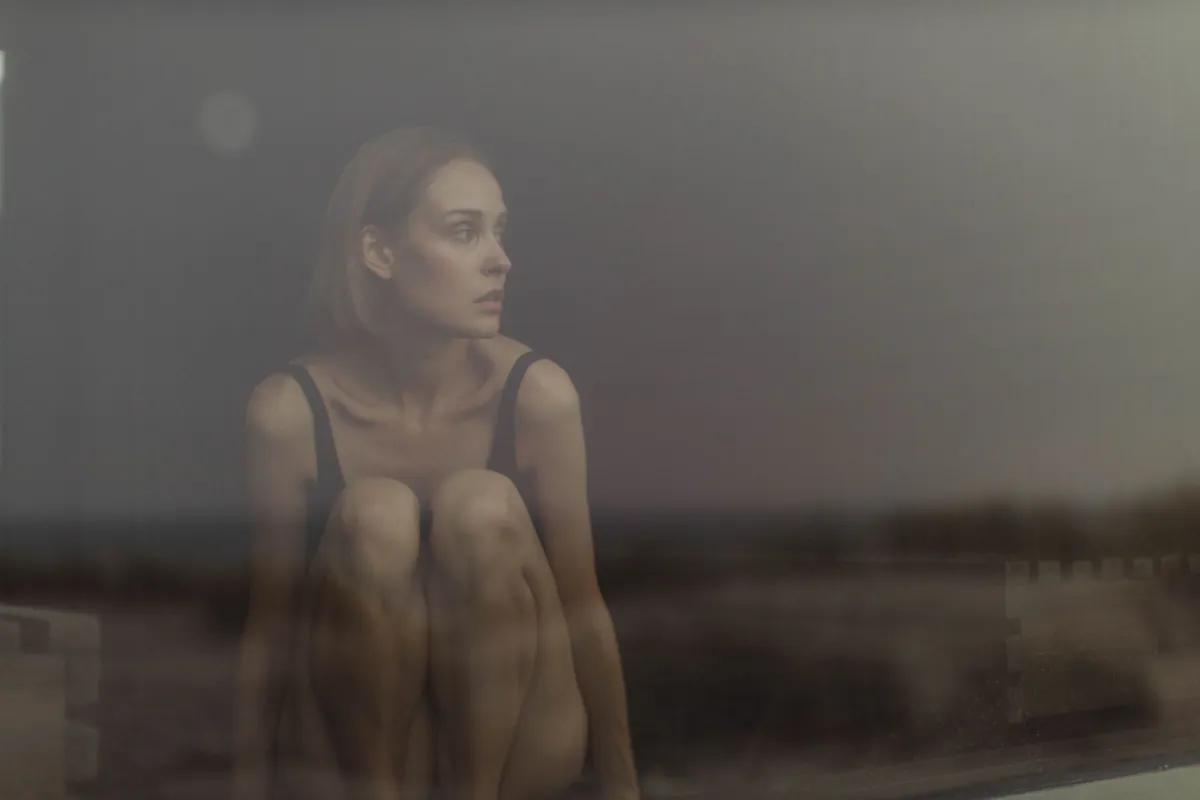 A contemplative woman sitting by a window, creating a serene and introspective mood.